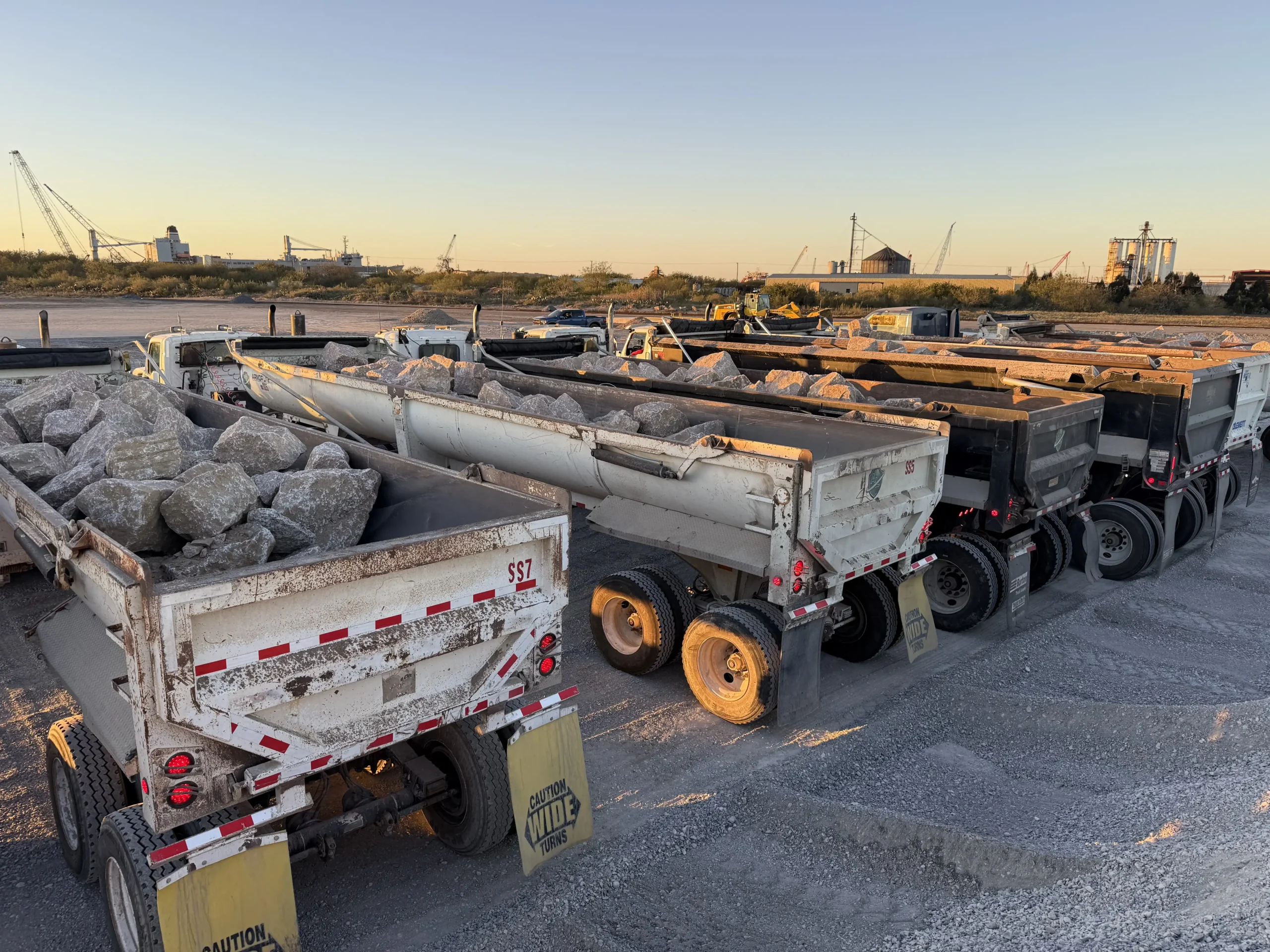 Line up of End Dumps ready for the day. Hauling 18x24 inch Riprap.