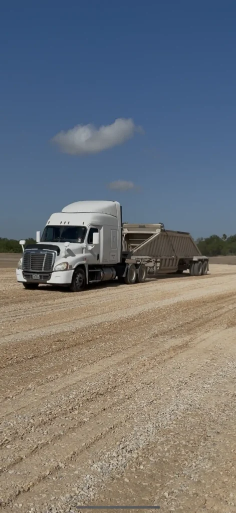 Belly dump truck carrying Limestone Base.